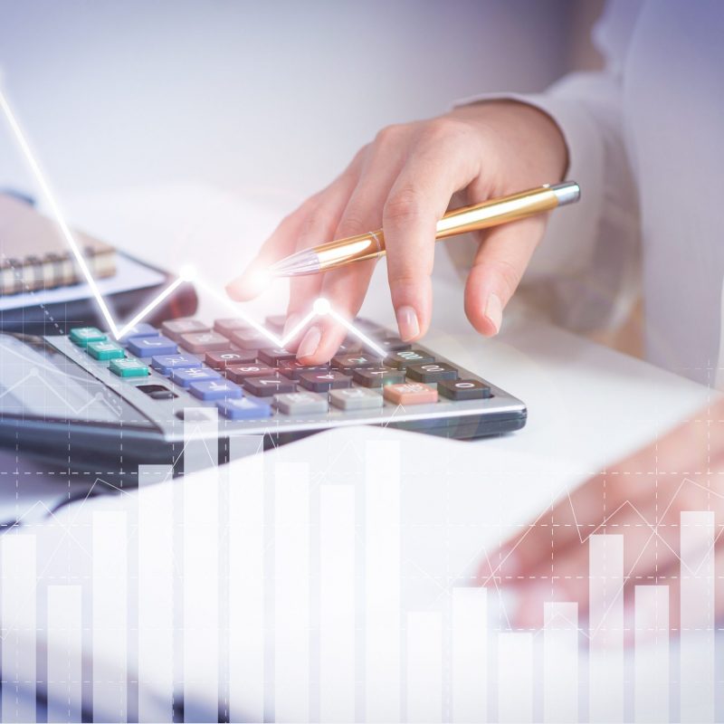 Accountant calculating profit with financial analysis graphs Accountant calculating profit with financial analysis graphs. Notebook, glasses and calculator lying on desk. Accountancy concept. Cropped view.